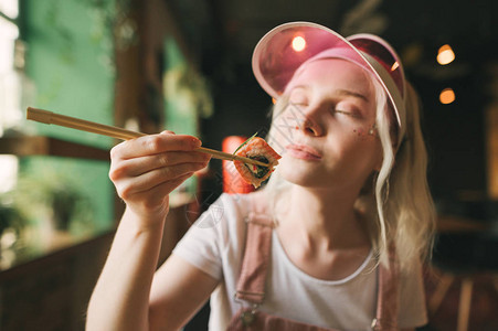 女孩拿着筷子和寿司卷的特写照片图片