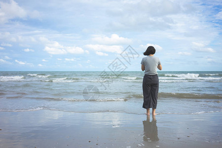 亚洲年轻女子面向大海站立图片