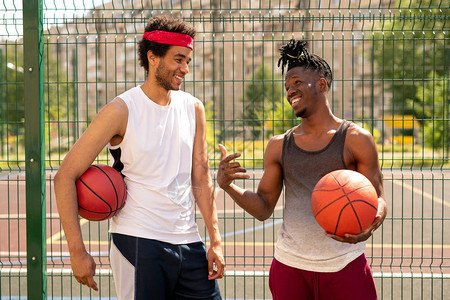 两个年轻的友好篮球玩伴讨论一些有趣的游戏时刻背景图片