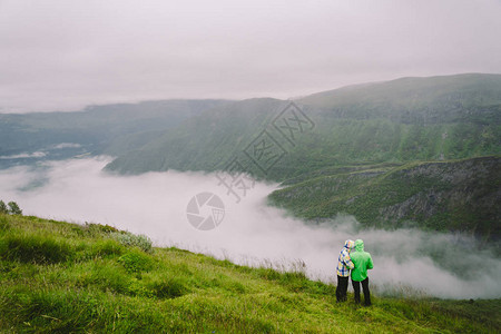 在挪威徒步旅行浪漫的情侣在悬崖边看美丽的风景情侣在观景台全景的背影一图片