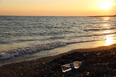 海水岸小石头沙滩和半空水瓶背景图片