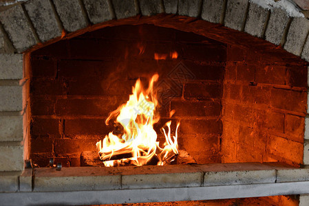 在烤箱中燃烧的木柴用石炉生火街边的火炉准备晚餐从火中冒烟砖墙SmokeSunlight背景图片