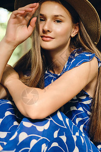 穿着蓝礼服戴帽子的年轻美女幻想着在城市公园里图片