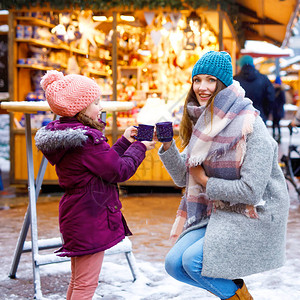 小可爱的女儿和母亲端着一杯热气腾的热巧克力或儿童拳快乐的儿童女孩和美丽的女人在德国的圣诞市场上圣诞节家图片