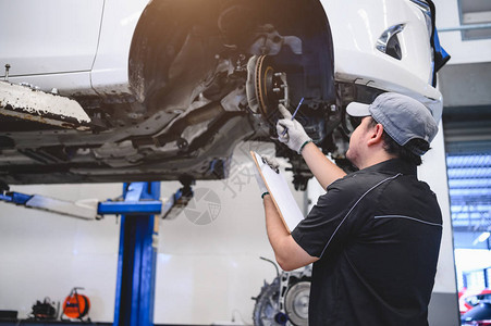 亚洲男汽车技师根据指定的车辆维修清单为客户进行汽车维修盘式刹车片磨损汽车修理车辆安全图片