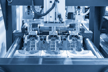 浅蓝色场景中PET瓶饮用水容器制造加工的吹塑模具操作用吹塑机制造的背景图片