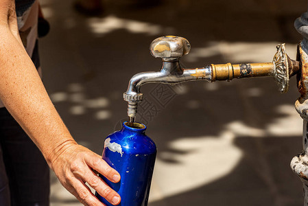 自来水水管在炎热的夏日用水龙头的水瓶装满一个水瓶时背景