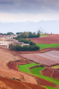 云南部风景秀丽的乡村东川红土地上美丽的麦田古老的村庄和山脉背景柔和的阳光春图片