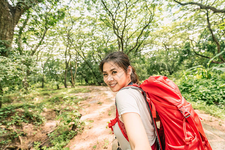 快乐的年轻徒步旅行者亚洲女旅行者背着包走在森林里冒险背包客旅行图片