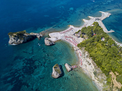 黑山的鸟瞰图夏威夷海滩遮阳伞和沐浴者以及清澈的海水锯齿状的海岸与陡峭的悬崖俯瞰着透明的大海野生自然和地中海背景图片