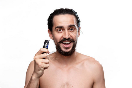 留着胡子的兴奋的大胡子男人拿着电动剃须刀图片