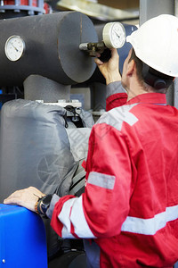 能源行业一名身着红色工作服和白色头盔的技术人员正在检查加热参数采暖配水技术电力行图片