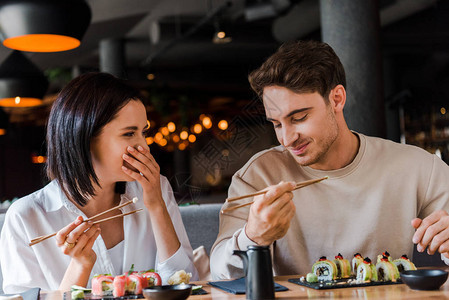 快乐的男子拿着筷子在开心的女人身边笑着在图片