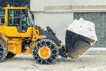 带钢金属链的大型装载机在冬季从高山区城市街道上清除大雪堆图片