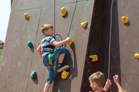 一个男孩在攀爬设备征服了人造塔顶在体育极乐娱公园图片