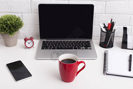 笔记本电脑前的红杯清晨咖啡台式办公桌面图片