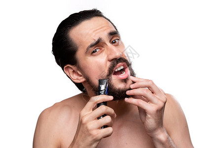 留着小胡子的英俊男人用电动剃须刀修剪他的胡子图片