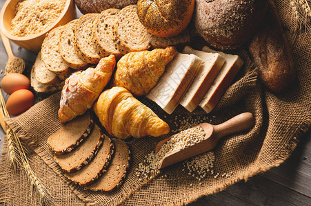 不同种类的面包与木制背景上的营养全谷物厨房概念中的食品和面包店美味的早餐gouemet和图片