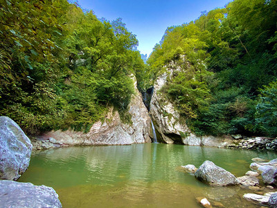 高山瀑布从悬崖掉落到一个清晰的湖泊图片