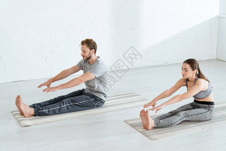 年轻男女在坐姿前屈体式中练习瑜伽图片