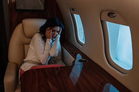害怕晕机的女人坐在私人飞机上摸头发图片