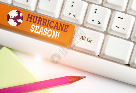显示飓风季节的书写笔记预计大多数热带气旋将开发白色pc键盘和白色背景上方的便条纸图片