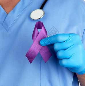 身穿蓝色制服和乳胶手套的医生拿着一条紫色丝带图片