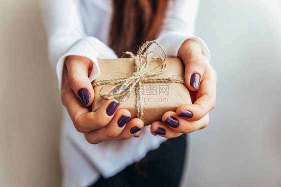 简单地设计女手拿着孤立在白色背景上的老式棕色礼品盒圣诞新年生日情人节庆祝礼图片