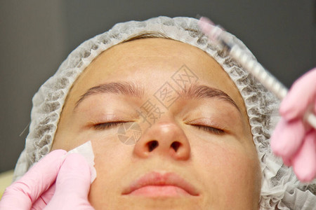 一位美容学家将肉毒素注射到女脸上的皱纹上图片