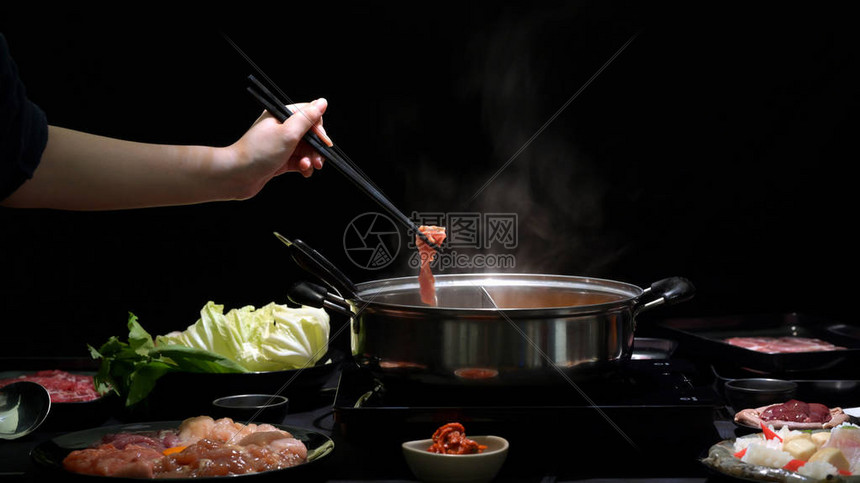 在热锅中用新鲜切片肉海产食品和黑本蔬菜吃ShabuShabuShabu的图片