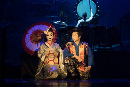传统和服的男女演员和狐狸马克坐在黑暗的舞台上图片