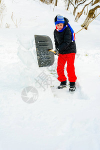 大雪过后小男孩用铲子扫雪图片