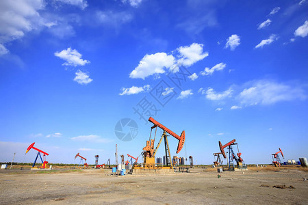 在油田石油泵正在运行蓝天和白背景图片