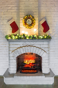 带火的白色壁炉为圣诞节装饰着蜡烛带礼物的圣诞老人袜子新年枞树枝和白砖墙上带大钟的花圈圣诞背景图片