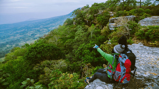 亚洲情人男女旅行自然旅行放松悬崖上的风景情侣在山上旅行欣赏山上的大气景图片