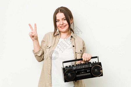 年轻的卷发女人拿着一个古老的电台欢乐和无忧虑地展示了和平图片
