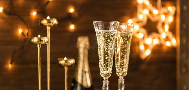 两杯香槟反对节日灯新年或圣诞节庆祝活动的象征除夕庆祝背图片