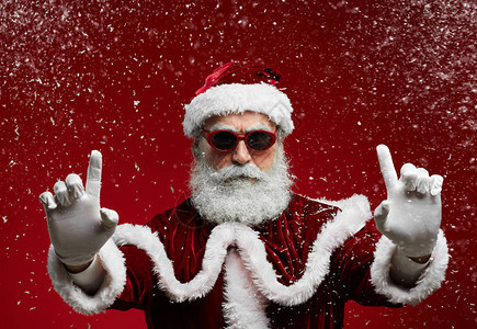 穿着太阳眼镜的酷圣诞老人在雪中享受圣诞晚会时微笑着图片