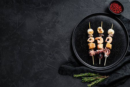 烧烤海鲜烤肉串配虾章鱼鱿鱼和贻贝黑色背景顶视图图片