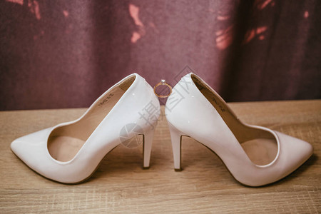两双白高跟鞋之间的金钻环红色背景的婚图片