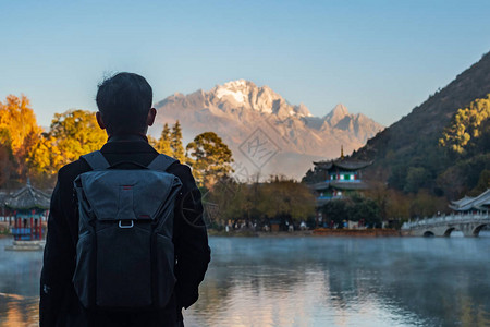 在玉龙雪山背景的黑龙池旅游的青年旅行者图片