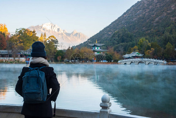 在玉龙雪山背景的黑龙潭旅游的年轻女游客图片