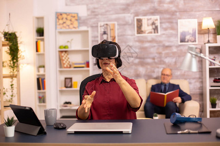 第一次在家中使用VR虚拟现实耳机的老妇人使用现代技术的活图片