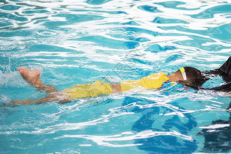 男孩穿着泳衣在教练的帮助下在游泳池里练习游泳健康生活方式的快乐体育活动图片