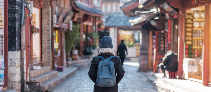 昆明九乡年轻女子旅行者在丽江古城广场街旅行背景