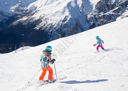 高山滑雪的小女孩在滑雪胜地的斜坡上滑冰图片