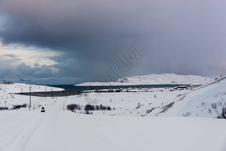 积雪覆盖的冬季道路通往俄罗斯科拉半岛北极圈上方最北端海上的一个小渔村路上的背景图片