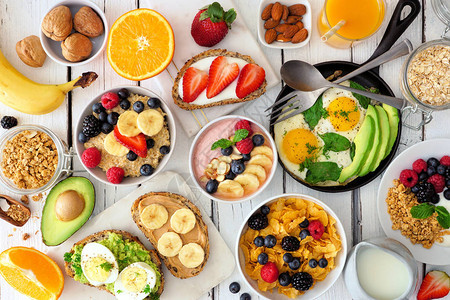 健康的早餐桌场景包括水果酸奶燕麦片冰沙碗麦片营养烤面包和煎锅在白色木背景图片