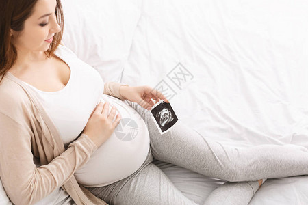 享受孕期的年轻女与婴儿超声波照片图片