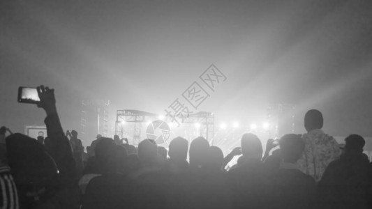 站在音乐会场地欢呼鼓掌的大观众人群的剪影使用智能手机在空中举起手来面对乐队享受舞台灯图片